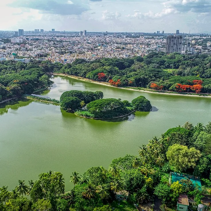 Bengaluru from above: a lake ringed with trees, the city behind it.