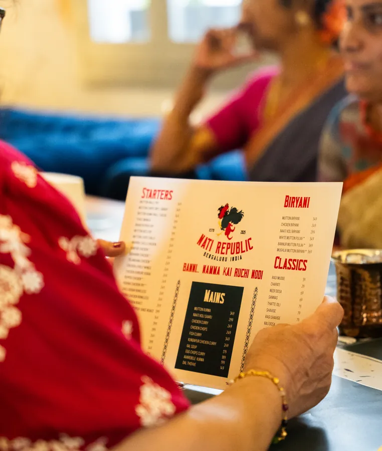 A server putting down a plate of Nati curry.