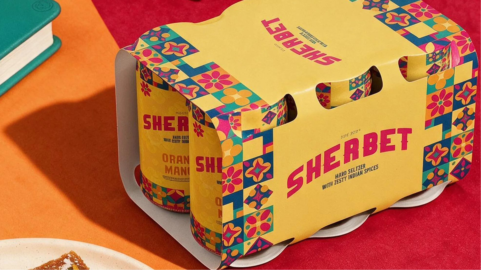 A Sherbet six-pack in its printed carton on a red and orange table.
